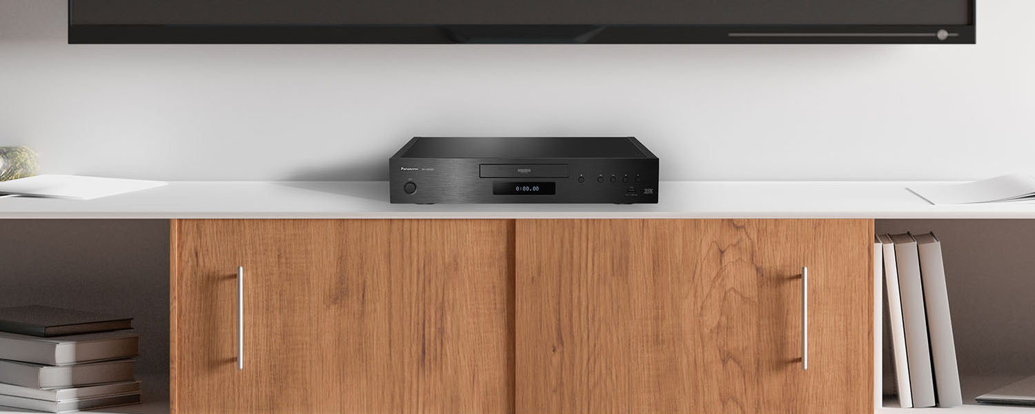 A high-end blu-ray disc player sits on a media console under a television