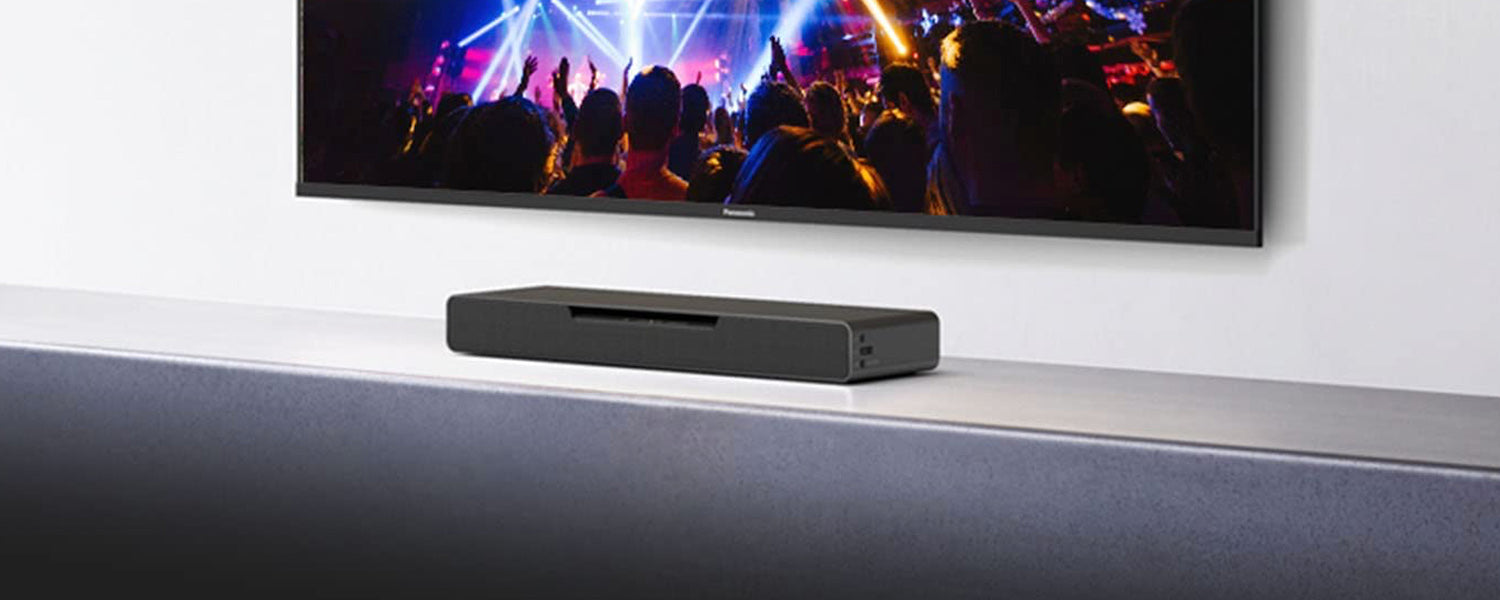 a compact soundbar sits atop a media console under a wall-hung television