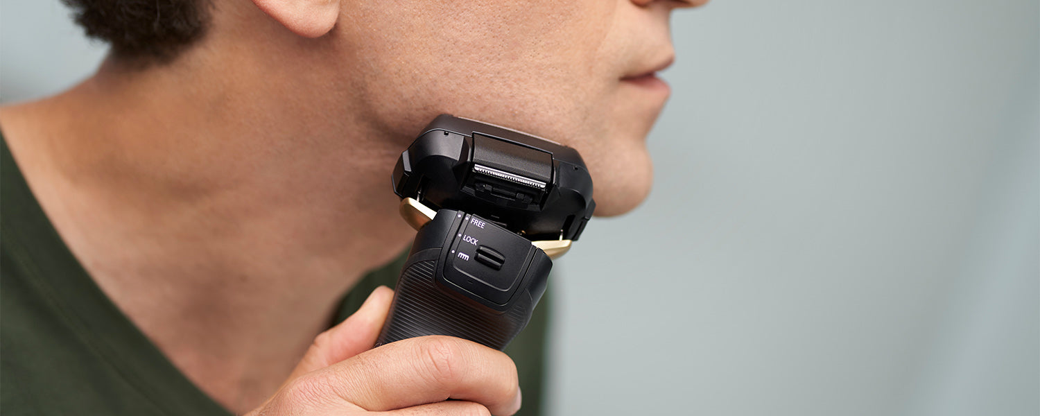 man using an electric shaver near his jawline