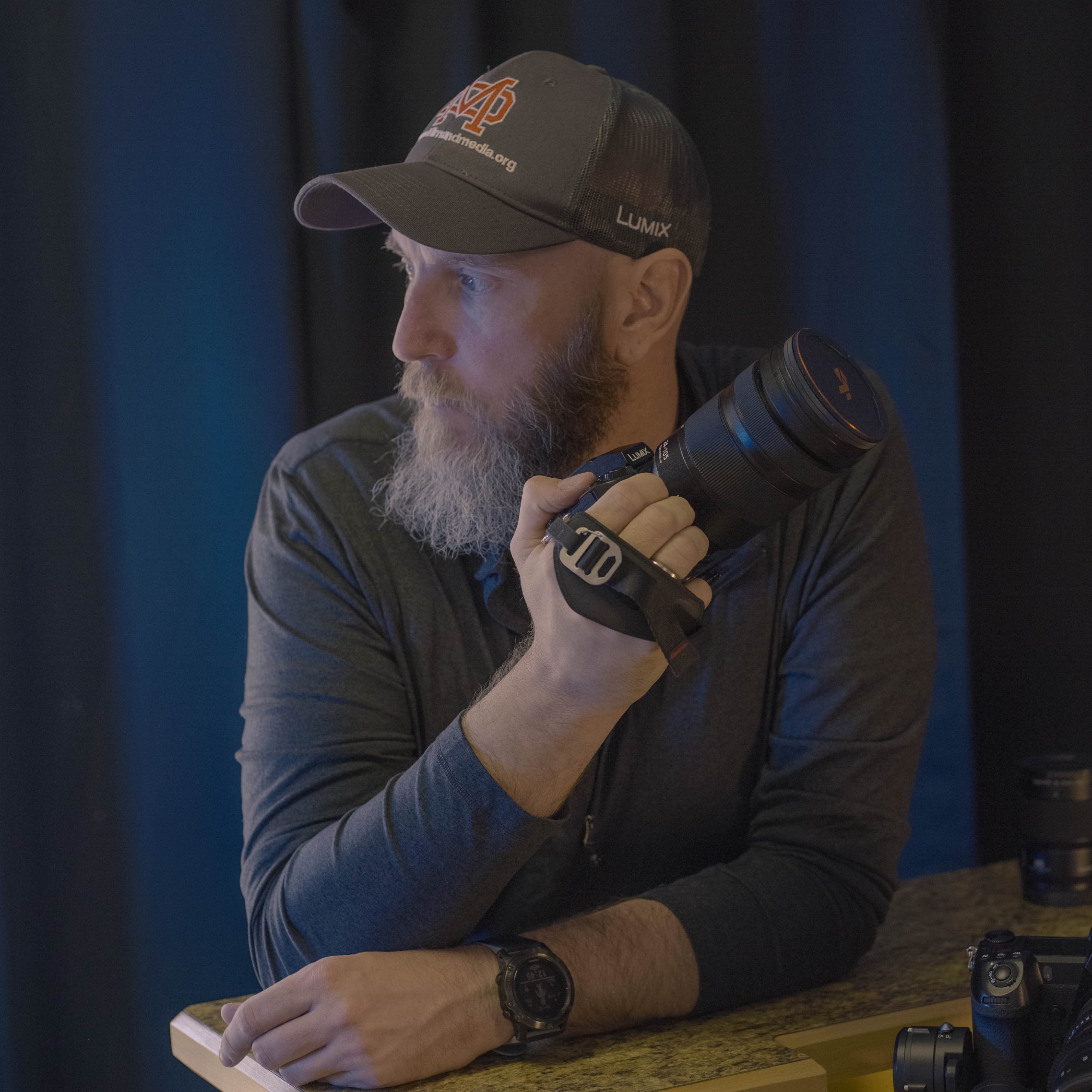 Photographer Andrew Roberts looks off into the distance as he holds his LUMIX camera in his hand