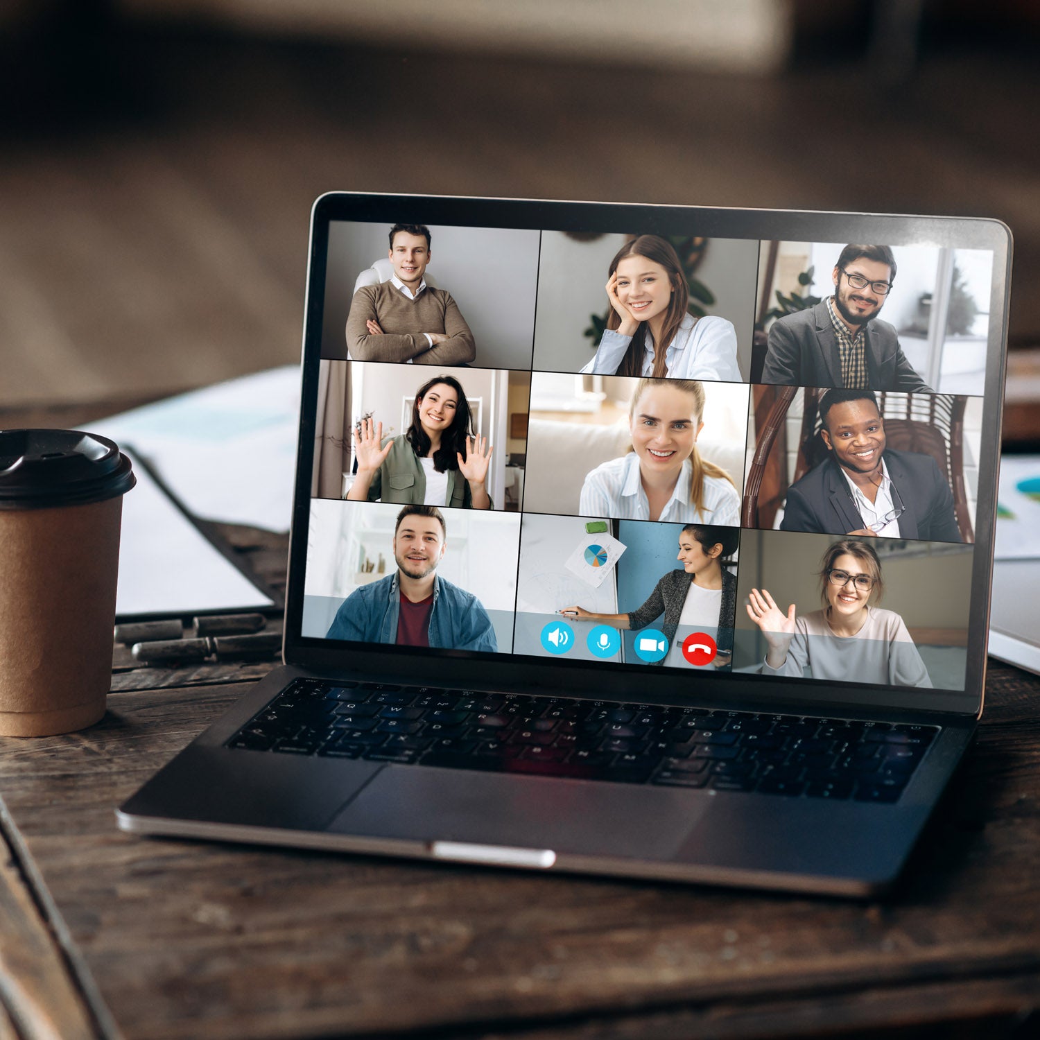 Laptop with a video call on a wooden desk with a coffee cup.