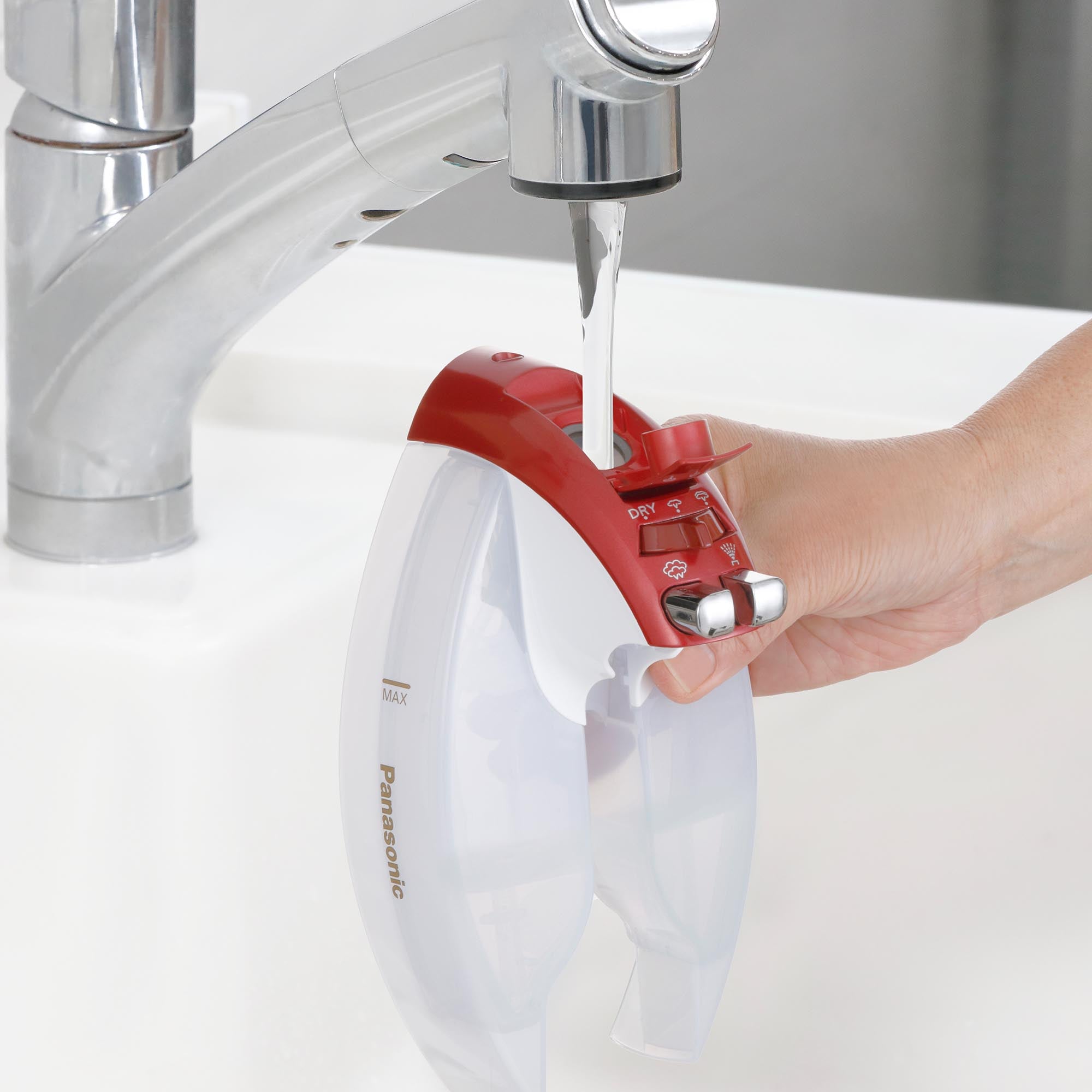 Filling the removable water tank of the Cordless Steam/Dry Iron, 1700W Wide Stainless Plate under a faucet.