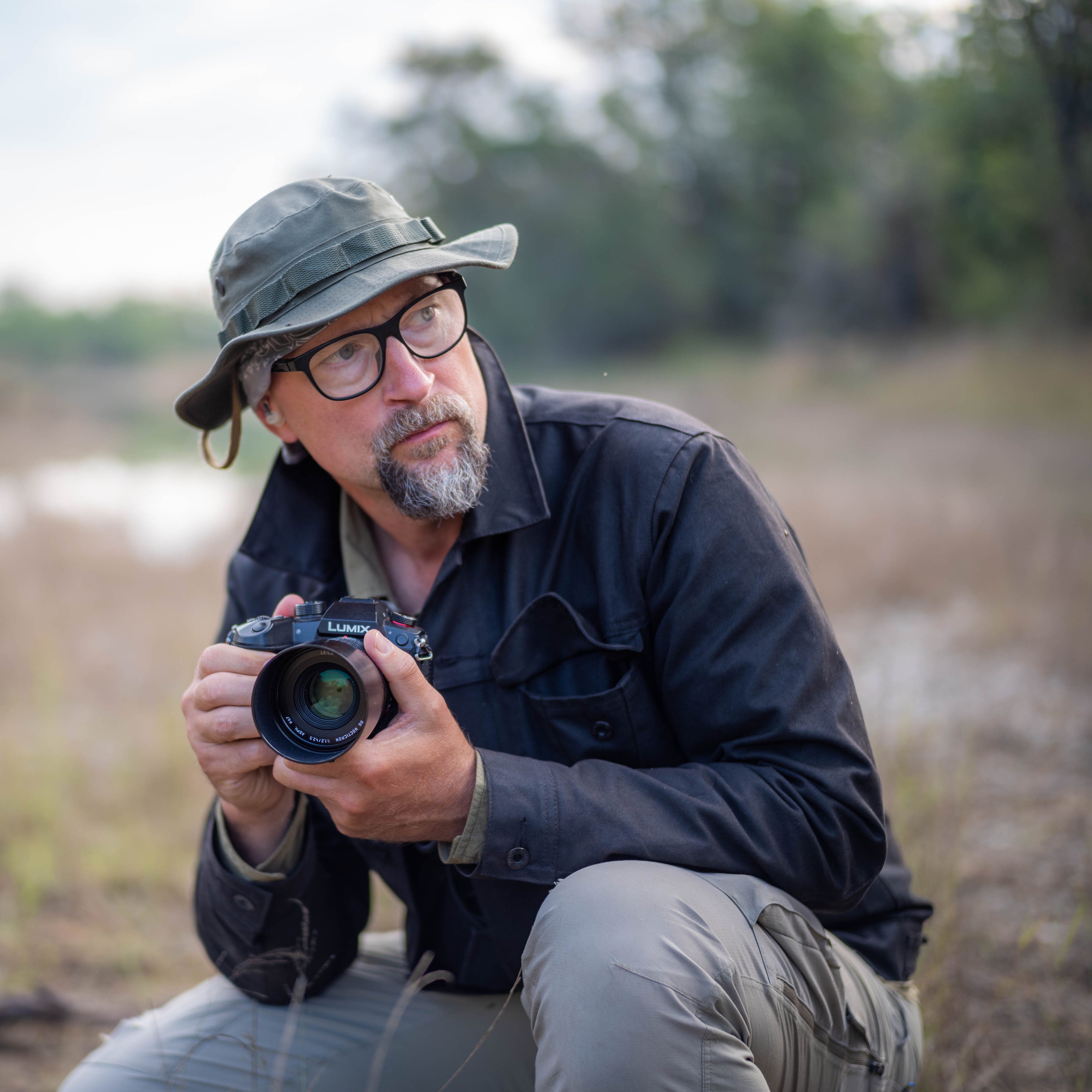 Photographer Ben Staley crouches down in the wilderness readying himself to take a photo with a LUMIX camera