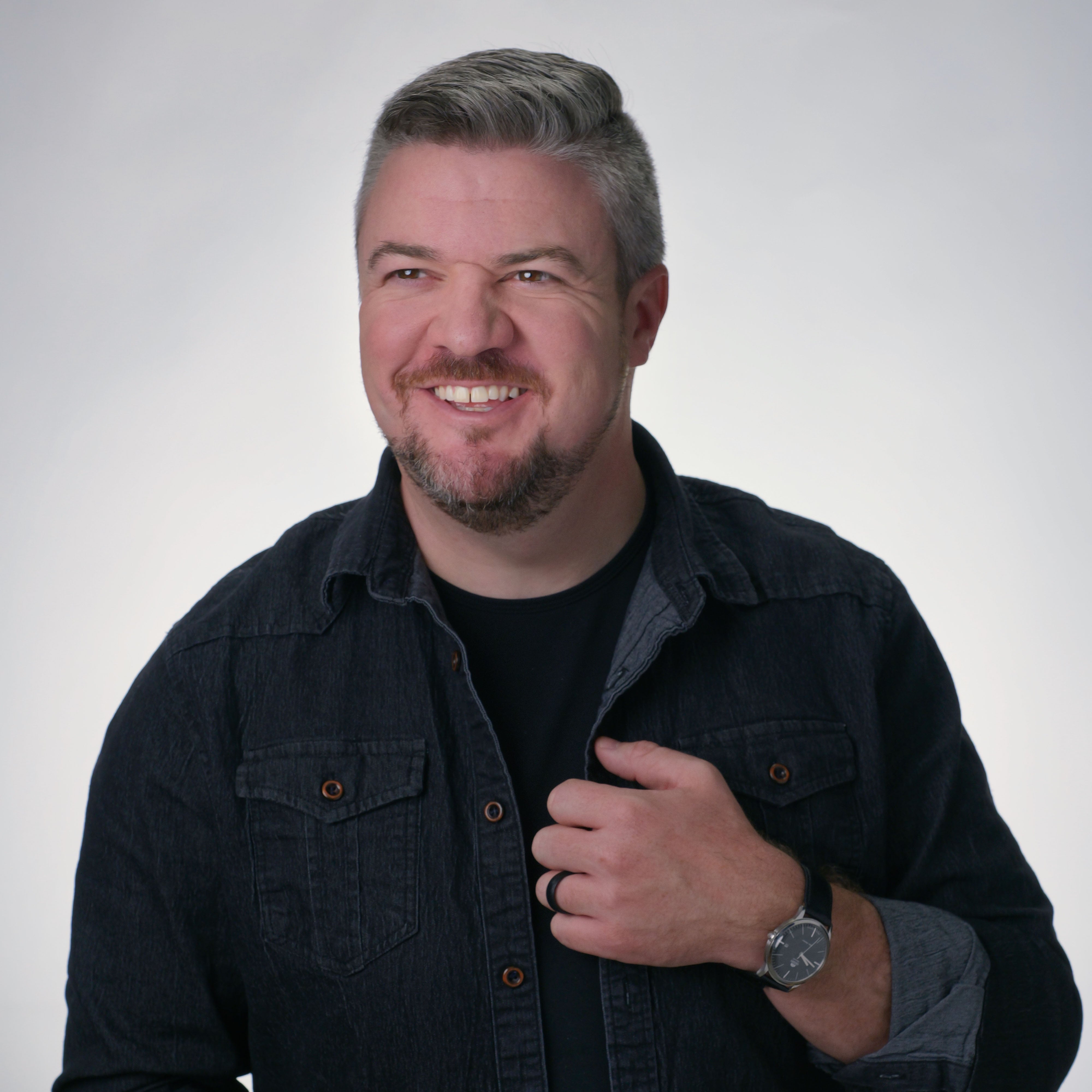 photographer Jordan bunch smiles as he poses on a white background