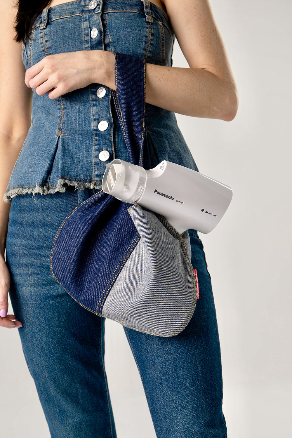 woman in denim outfit holding a demin purse with a white hair dryer peaking out