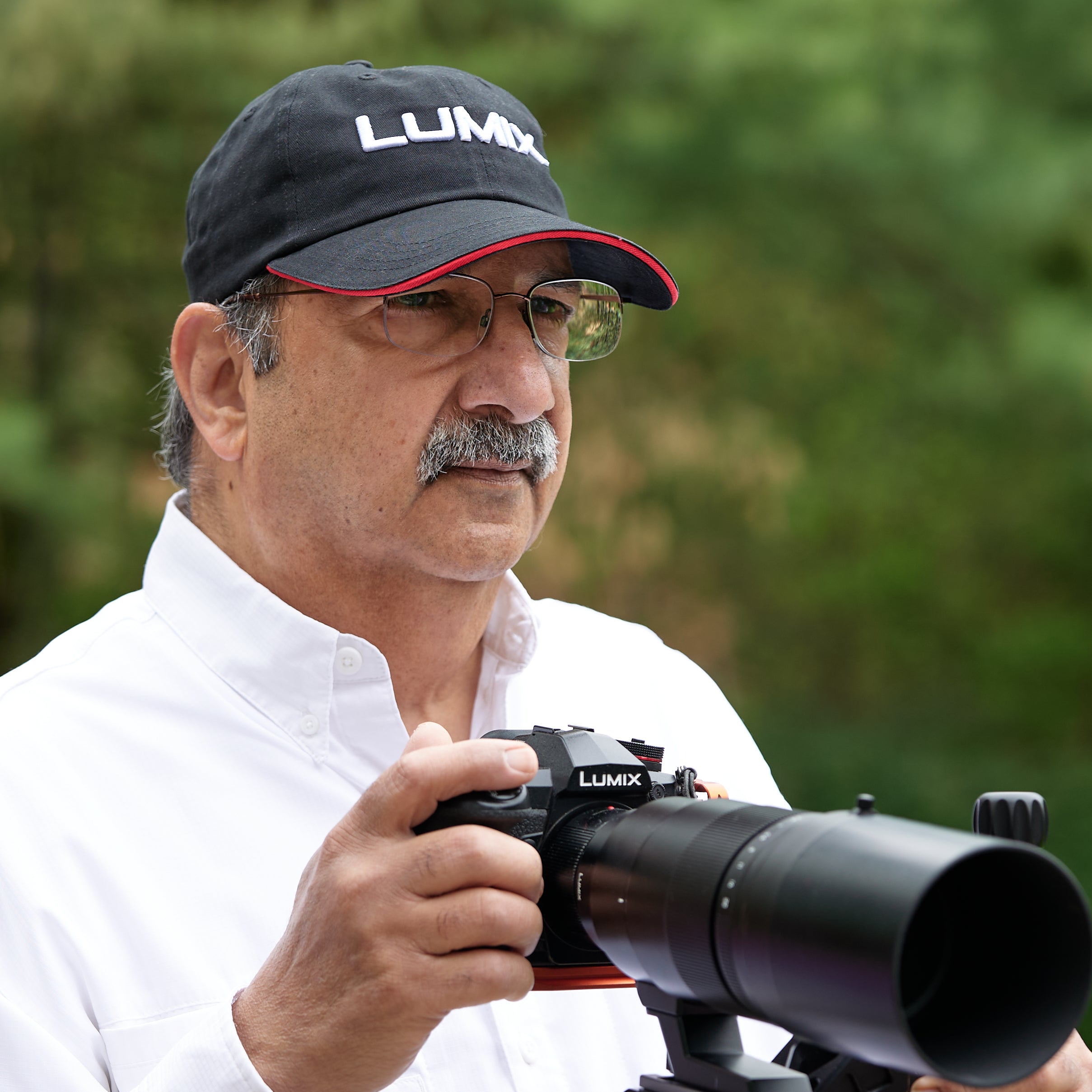 Photographer Shiv Verma wears a LUMIX baseball cap and readies his LUMIX camera with extra-long lense